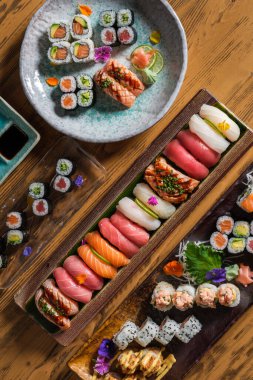 Enfes geleneksel Japon suşisinin üst görüntüsü ve tepsilerde ve açık kafede servis edilen taze balıklı rulo.