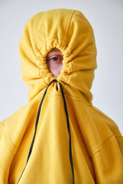 Gri arka planda kameraya bakarken gözlerinin etrafına sarı başlık takan çocuk