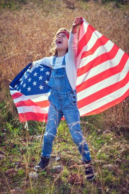 Kırsal kesimde Amerikan bayrağıyla kollarını kaldırırken tüm çocuk mutlu bir şekilde gülüyor.