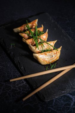 Tahta çubukların yanında Frenk soğanı olan lezzetli Asya gyozası.