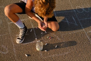 Yazın asfalt zeminde seksek oynayan rengarenk tebeşir parçalarıyla tanınmayan reşit olmayan bir çocuktan.