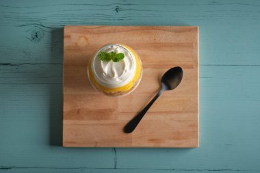 Mavi ahşap masadaki kesme tahtasında servis edilen nane yaprağıyla süslenmiş tatlı cheesecake 'in üst manzarası.