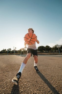 Sahada antrenman yaparken basketbol antrenmanı yapan kararlı bir çocuk.