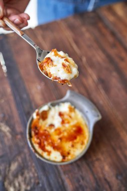 Yukarıdan gelen isimsiz kişi, ahşap masaya koyarken lezzetli kavrulmuş pirinç pudinginden kaşıkla malzeme alıyor.