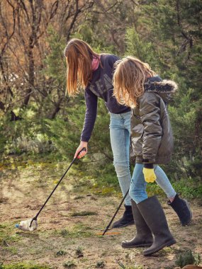 Çevresel kampanyaya katılırken çöp toplayan ve çöp toplayan genç kızların yan görünüşü