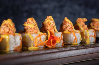 Somon ve taze sosla kaplanmış iştah açıcı suşiye yakın. Restoranda çiçekler ve bulanık arka planla servis ediliyor.