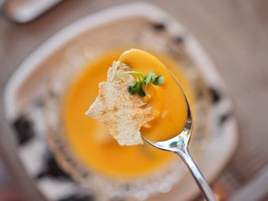 Kaşığın iştah açıcı çorbasının üst görüntüsü kafeteryadaki masaya yerleştirilmiş tabakta mikro yeşiller.