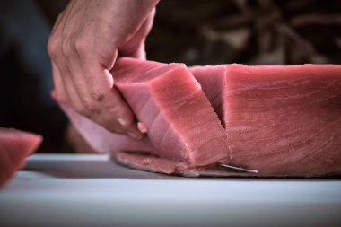 Bir şefin erkek elleri Lezzetli bir fileto taze mavi yüzgeçli ton balığı kesiyor.