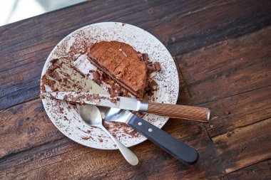 Pastanın sol üst kısmının, parti sırasında ahşap masaya yerleştirilmiş dağınık kaşık bıçağı sunucusu.