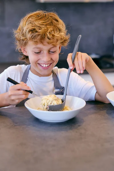 Vrolijk Kind Met Kom Heerlijke Romige Pasta Lepel Aan Keukentafel — Stockfoto