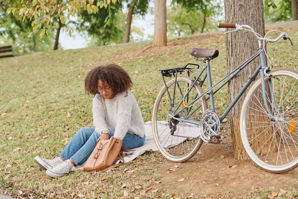 Ganzkörper Afroamerikanerin Sitzt Neben Fahrrad Und Sucht Tasche Während Sie — Stockfoto