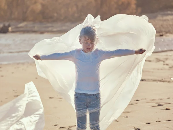 プラスチック製のフィルムに包まれた伸ばされた手で立っている平和な19歳の少年は 晴れた日の汚染された砂浜の岸から拾いました — ストック写真