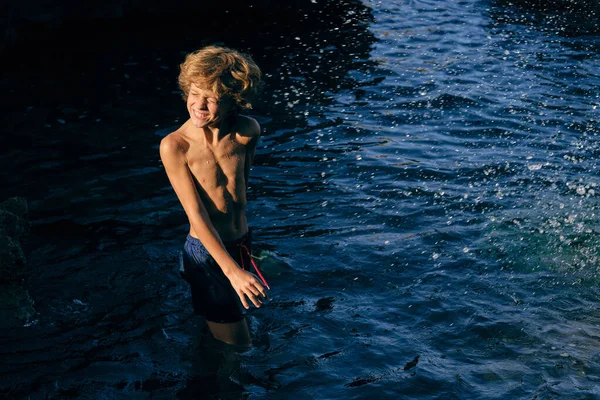 Dítě Plaveckých Trenýrkách Zavřenýma Očima Dělá Obličej Oceánu Stříkající Vodou — Stock fotografie
