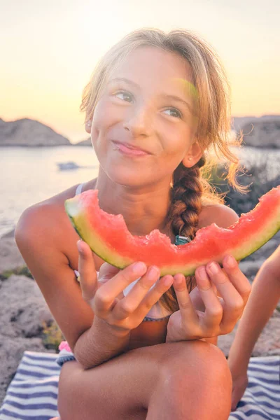 在阳光明媚的夏夜 穿着游泳衣 一边吃着美味的西瓜 一边坐在野餐毛毯上 快乐的孩子 — 图库照片