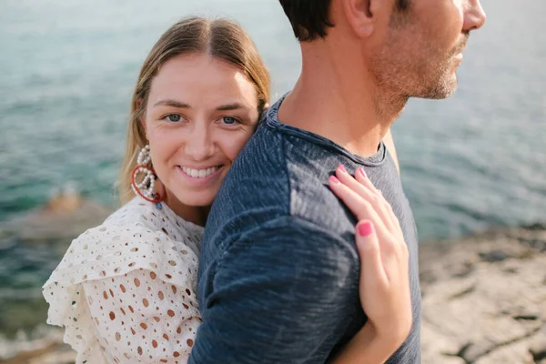 여자가 여름날 해변에서 남자를 껴안고 웃으면서 카메라를 있습니다 — 스톡 사진