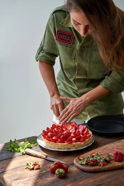 若い女性シェフの高い角度で緑のシャツでおいしい健康イチゴパイを提供 — ストック写真