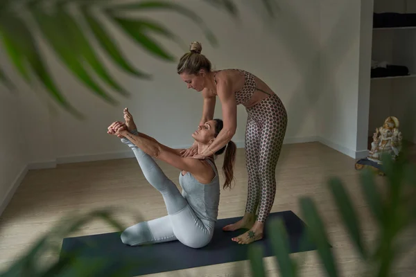 在现代工作室的瑜伽训练中 女运动员穿着运动服练习在黑垫子上摆姿势的侧视图 — 图库照片