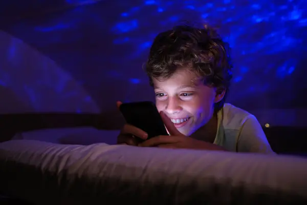 Оптимистичный Мальчик Улыбается Пишет Смс Социальных Сетях Мобильном Телефоне Лежа — стоковое фото
