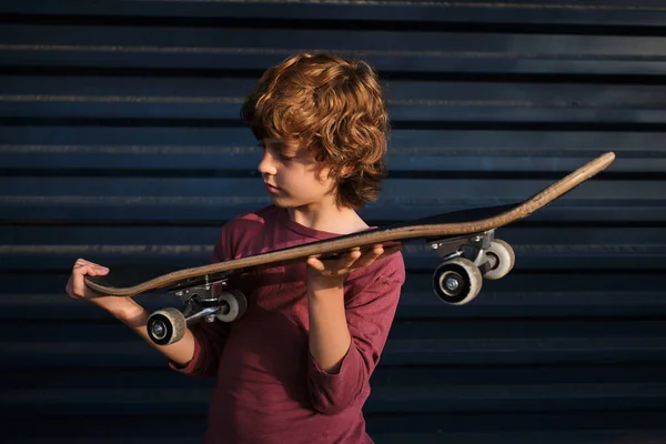 Petit Patineur Vêtements Décontractés Examinant Skateboard Tout Tenant Contre Mur — Photo