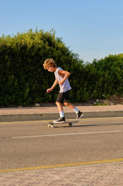 Zijaanzicht Van Knappe Jongen Paardrijden Skateboard Langs Asfaltweg Zonnige Dag — Stockfoto