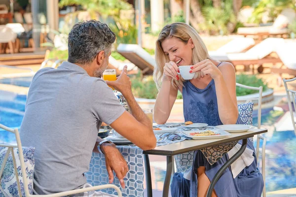 阳光明媚的日子里 快乐的女人一边喝咖啡 一边和男人一起在游泳池边的度假胜地喝果汁 — 图库照片