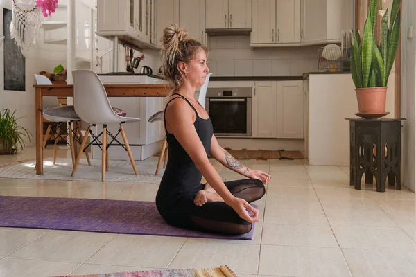 在家里练习瑜伽时 身穿运动服的年轻女子站在荷花垫上的侧视图 — 图库照片