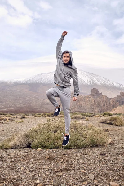 スペインのカナリア諸島のテネリフェ島にあるTeide火山の近くで休んで勝利を喜びながら 上昇拳でジャンプする陽気な若い男性旅行者の完全な体 — ストック写真