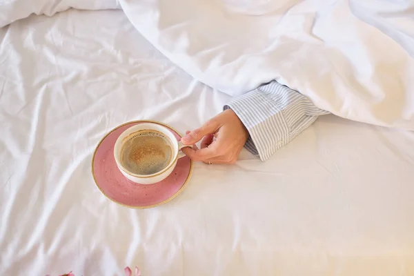 从上面的庄稼妇女 一杯香浓的咖啡 放在粉红的盘子里 早上在床上休息 — 图库照片