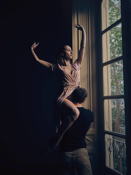 Kollarını Kaldırmış Esnek Balerin Pencerenin Yanında Güçlü Isimsiz Bir Erkek — Stok fotoğraf