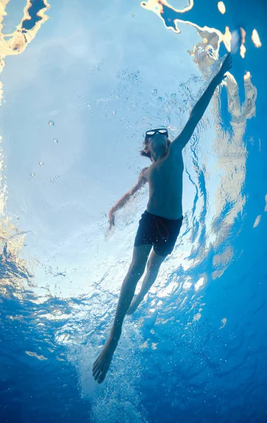 休暇中にきれいなプールで泳いでダイビングゴーグルを身に着けているアクティブな男の子の下から — ストック写真