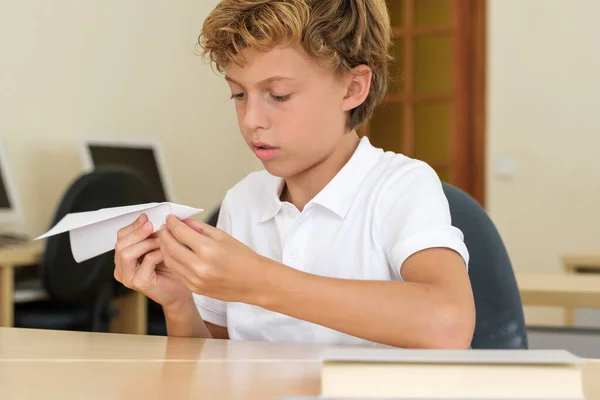 Konzentriertes Schulkind Kreiert Weißes Papierflugzeug Während Der Schule Schreibtisch Sitzt — Stockfoto