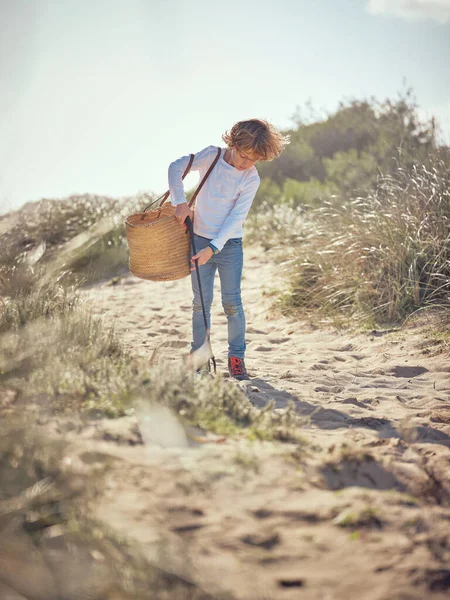 ビニールの廃棄物を拾うウィッカーバッグと日当たりの良い日に砂浜の地面にゴミのグラバーとゴミのボーイの全身 — ストック写真