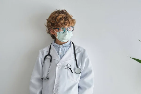 Kontemplacyjne Dziecko Okularach Jednorazowej Masce Stetoskopem Mundurze Medycznym Odwracając Wzrok — Zdjęcie stockowe