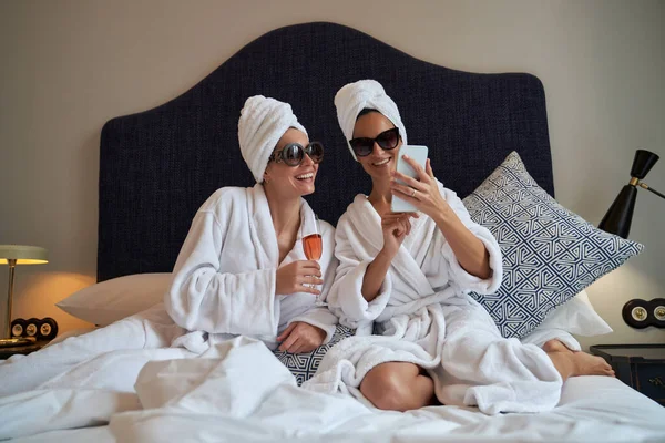 Gelukkige Vrouwelijke Vrienden Een Zonnebril Handdoek Tulbanden Badjas Zittend Bed — Stockfoto