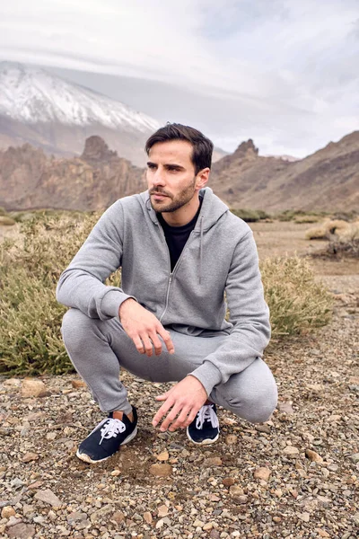 Full Body Unshaven Pensive Male Activewear Sneakers Sitting Squat Rocky — Stock Photo, Image