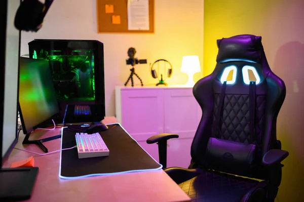 Modern cihazlar bağlı klavye neon ışıkları PC video kamera kulaklıkları ve aydınlık odaya yerleştirilmiş rahat başlık koltuğu.