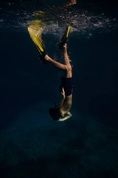 深海水の下で泳ぐシュノーケリングマスクとスリッパで匿名の男性ダイバーの完全なボディサイドビュー — ストック写真