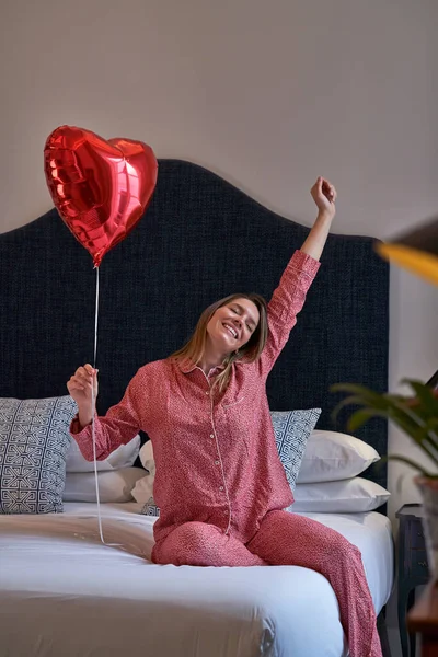 Kırmızı Kalp Şeklinde Bir Balonla Yatakta Oturan Mutlu Kadın Doğum — Stok fotoğraf