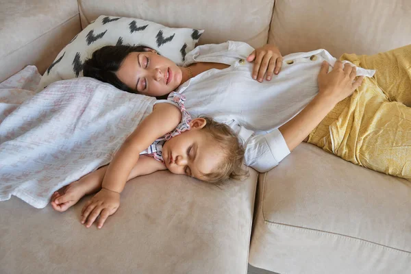 从上面看 年轻的母亲和可爱的小宝宝被毛毯覆盖着睡在客厅里的沙发上 — 图库照片