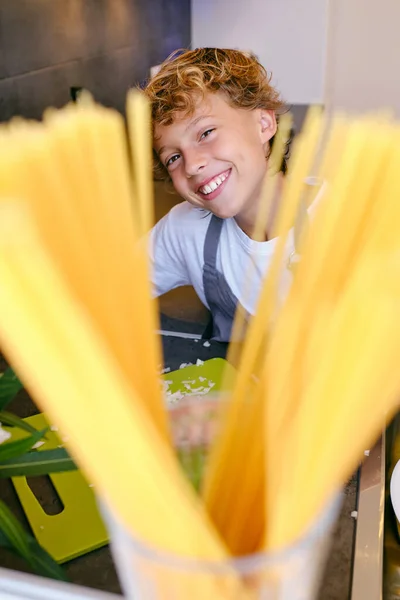Szczęśliwe Dziecko Patrząc Aparat Przed Cięcia Cebuli Niegotowane Spaghetti Jasnej — Zdjęcie stockowe