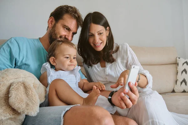 Glada Föräldrar Med Dotter Sitter Soffan Och Tittar Video Mobiltelefon — Stockfoto