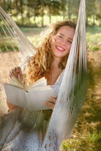 Optymistyczna Młoda Kobieta Długimi Włosami Uśmiechnięta Patrząca Kamerę Czytając Dobrą — Zdjęcie stockowe