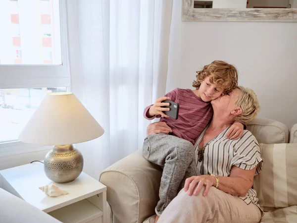 Preciosa Abuela Besando Abrazando Lindo Niño Con Teléfono Inteligente Mientras — Foto de Stock