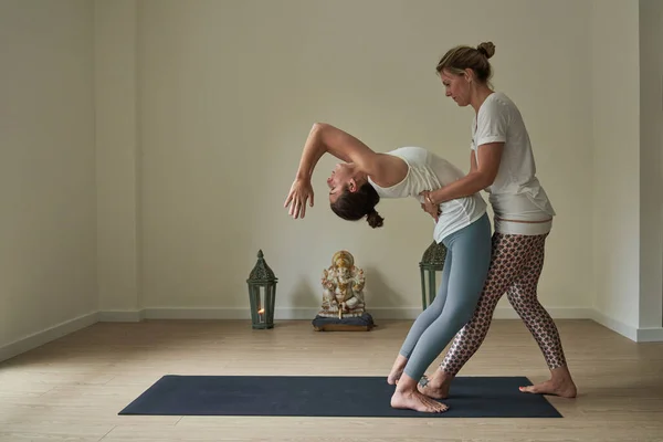 在瑜伽课期间 侧看全身上下都是女教练 她们穿着运动服 帮助做瑜伽的妇女在垫子上做运动 — 图库照片