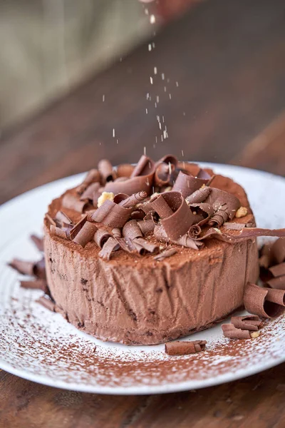 用巧克力釉料装饰的美味巧克力蛋糕和盘子里的刨花 — 图库照片