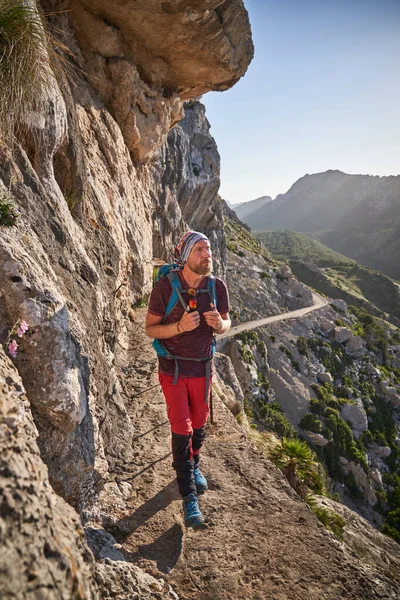 ラフ斜面近くの狭い山道をバックパック歩くと絵のような景色を楽しむと中年男性観光客のフルボディ — ストック写真