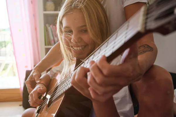 ブロンドの女の子は ソファの上に彼女と座って 家で彼女を教えている女性と微笑んでギターを弾いています — ストック写真