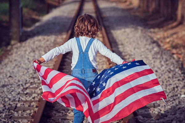 Pohled Zezadu Nepoznatelné Dítě Džínové Kombinéze Železnici Vlající Vlajkou Ameriky — Stock fotografie