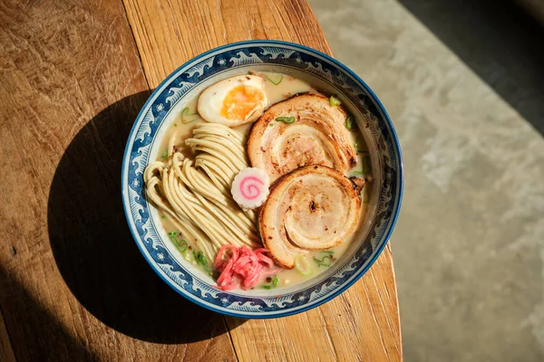 Japon restoranında öğle yemeği sırasında güneşli masanın kenarına konmuş lezzetli ramen tabağı.