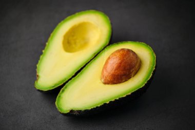 Siyah arka planda izole edilmiş taze yeşil organik avokadoyla kesilmiş bir fotoğraf..